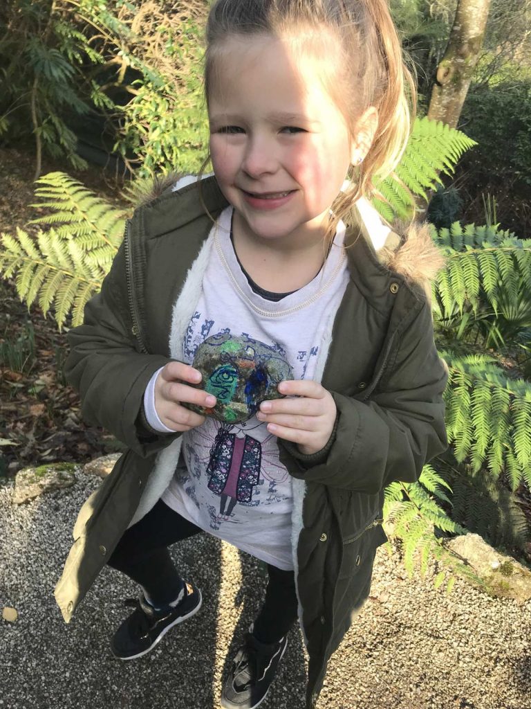 Girl poses with painted pebble she found at Trelissick Gardens. Part of the Kernow Rocks! initiative. Go seeking for hidden painted rocks